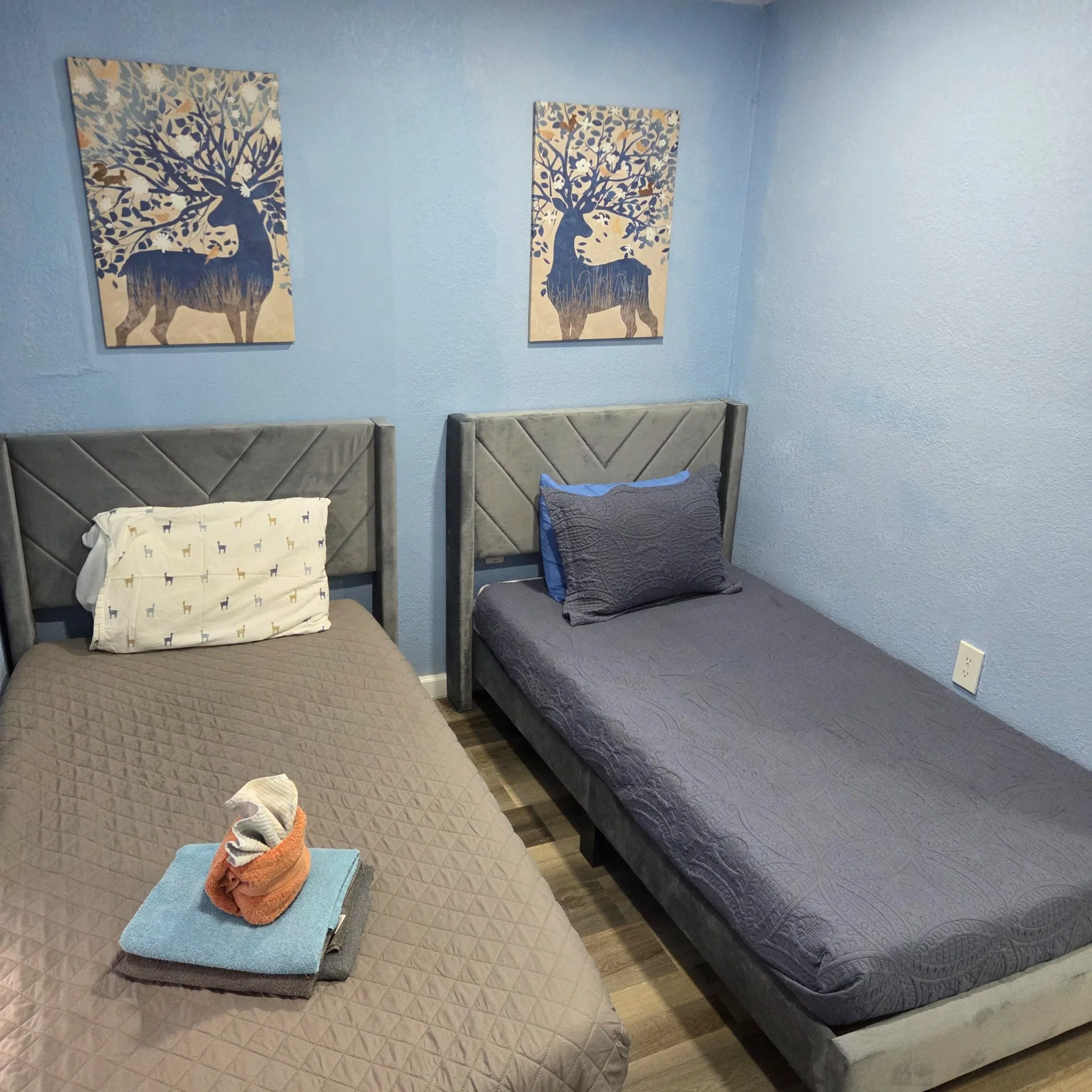Original Bedroom with two single beds, blue walls, and decorative wall art above the beds.
