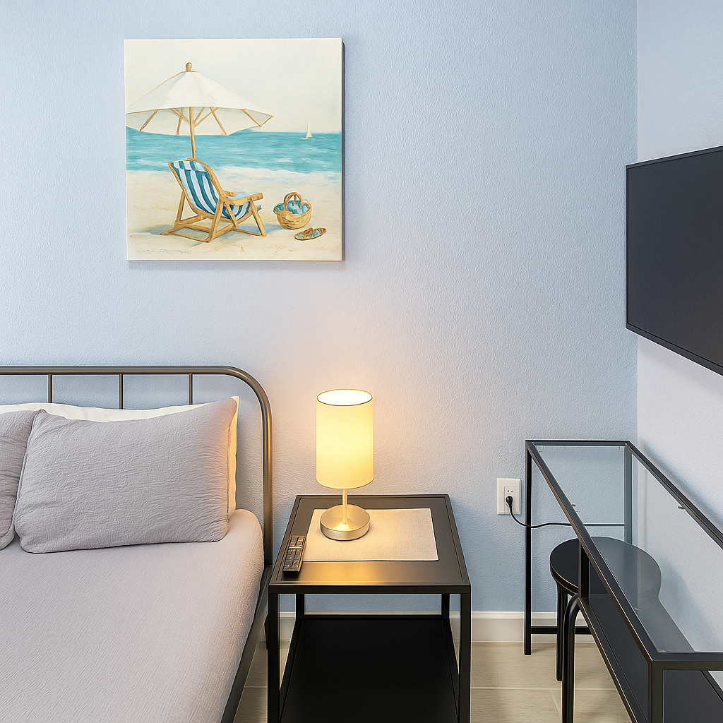 Enhanced Bedroom corner with a bed, bedside table, lamp, beach painting, and a wall-mounted TV.