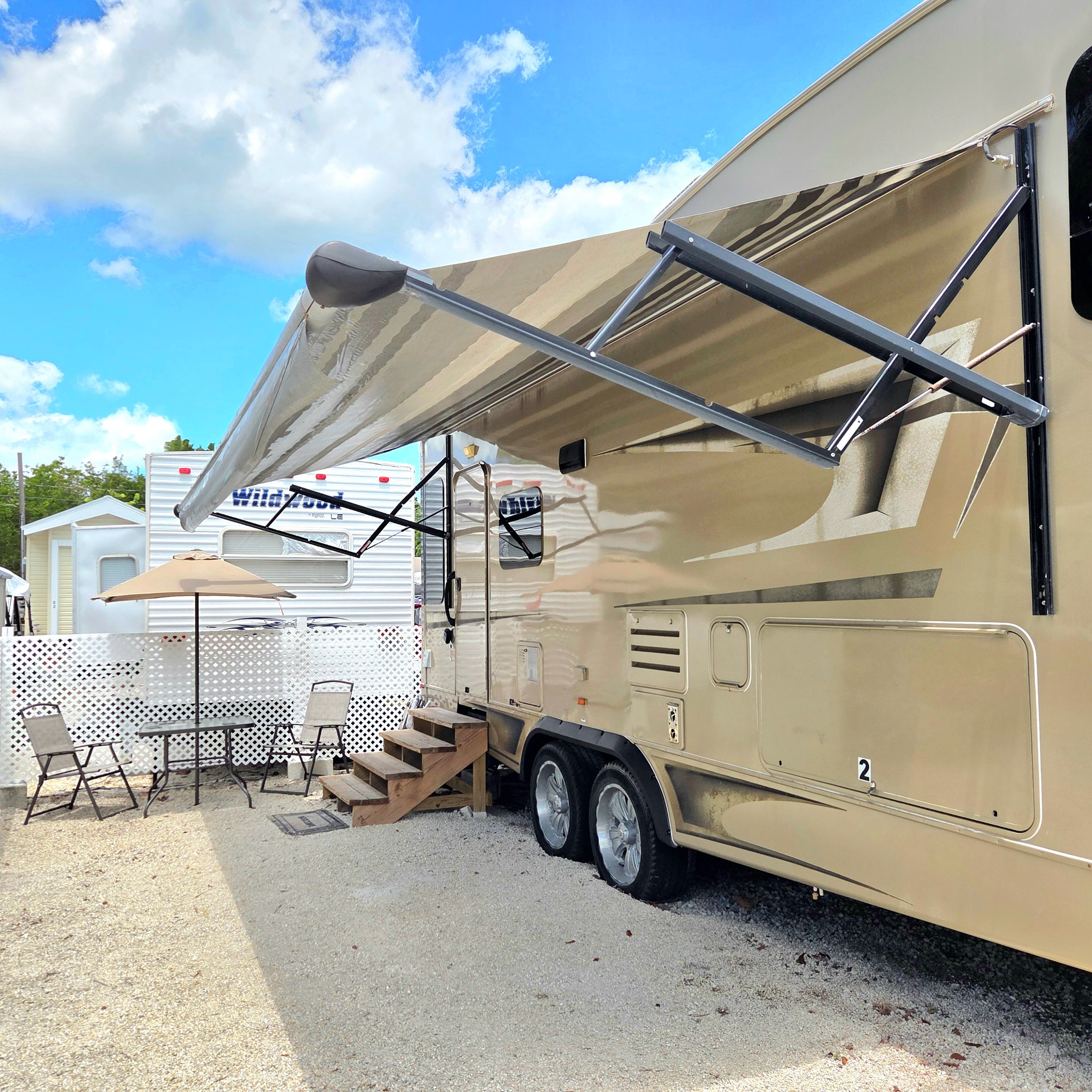 Original Real estate property photo: The photo of the outdoor recreational vehicle area is well-composed with good lighting. However, the image can benefit from slight adjustments to enhance the sky’s vibrancy and ensure the vehicle's details are crisp and clear. Neutral color balance should be maintained to reflect an accurate depiction while slightly boosting the brightness and contrast.