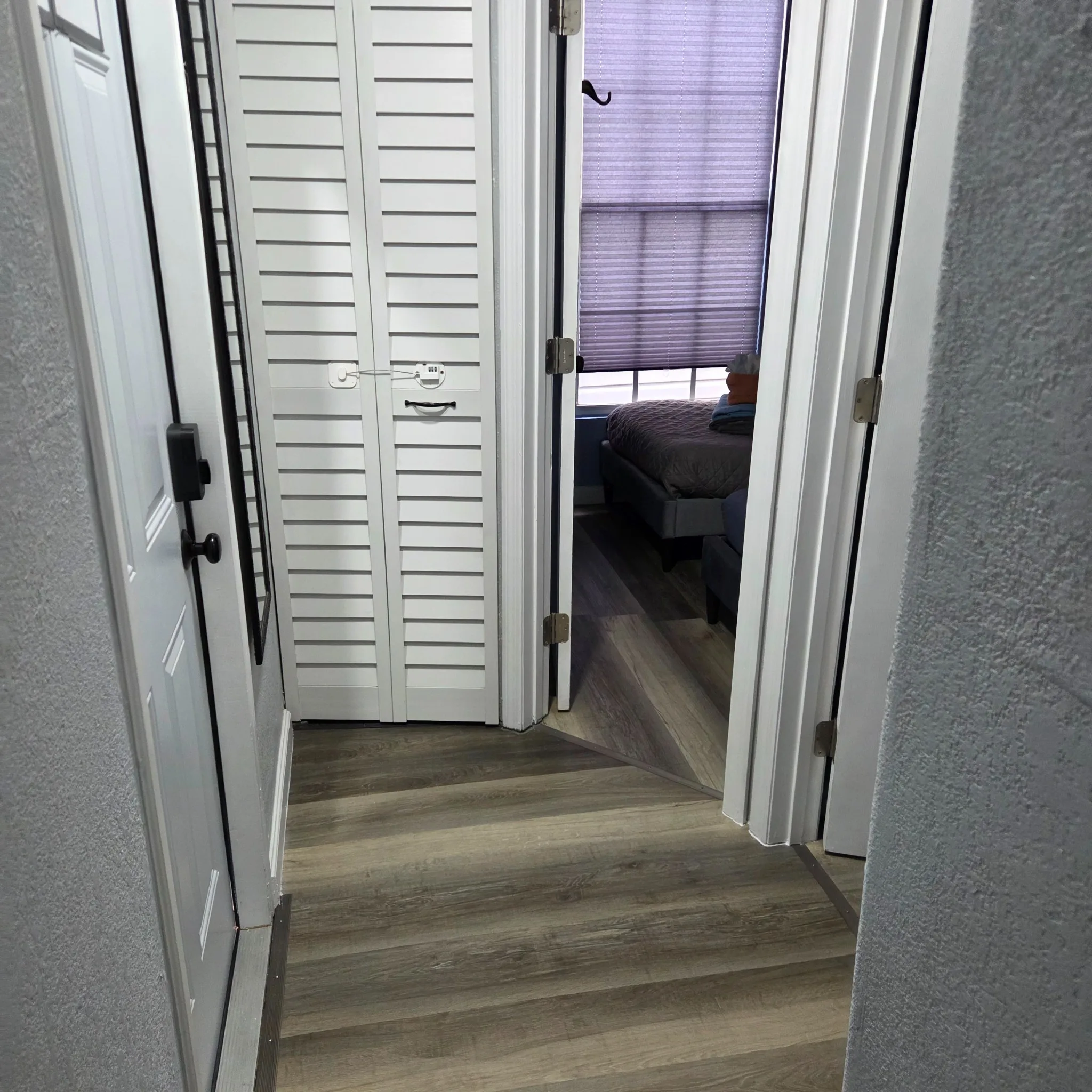 Original Hallway with wooden floor leading to a bedroom, featuring a closet with louvered doors.